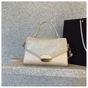 Chic beige envelope handbag with metal lock on a grey stone surface for office style