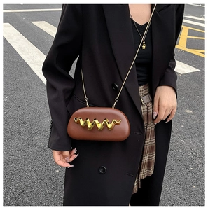 Detail of a brown capsule-shaped crossbody bag with gold wave metal and chain strap