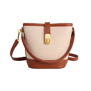 Fashionable beige canvas bucket bag with brown leather trim and gold metal hardware