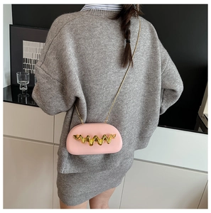 Pink semi-circular crossbody bag featuring a golden wave trim and metal chain strap