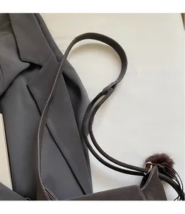 Detail of matte dark brown bucket bag with a smooth long strap and fur ball charm