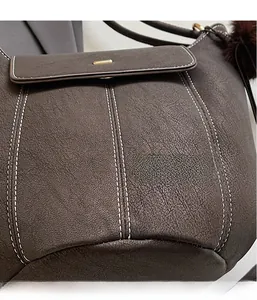 Close-up of matte brown leather texture with white contrast stitching and gold buckle detail