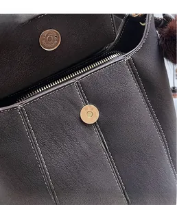 Macro view of dark brown leather bucket bag with contrast stitching and golden hardware
