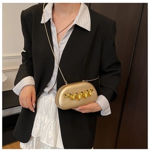 Detailed view of a gold capsule crossbody bag with 3D wave ornaments and chain strap