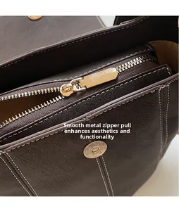 Close-up of golden zipper puller and round magnetic buckle on dark brown leather bag