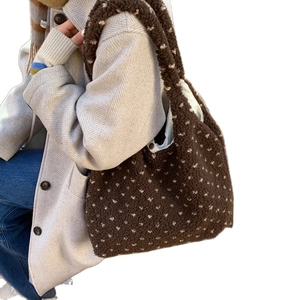 Brown faux shearling tote bag with white polka dots worn over a shoulder for winter