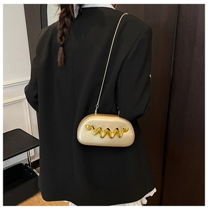Close-up of champagne gold acrylic clutch bag with wavy metal decor and chain strap