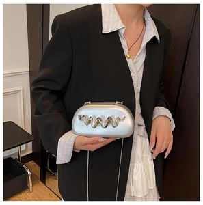 Silver hard-shell clutch bag with wave metal bars worn on a black blazer