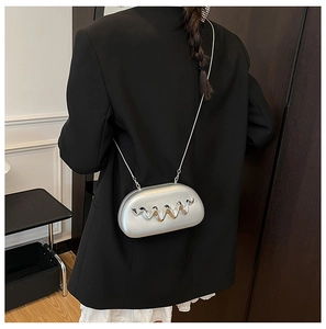 Detail of silver metallic crossbody bag with wave cutout pattern on a black blazer