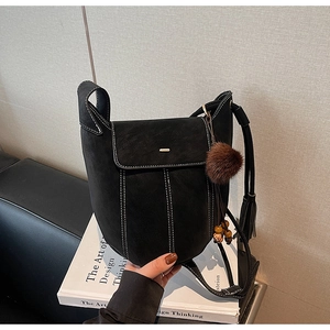 Detail of matte black bucket bag showing white contrast stitching and tassel charm