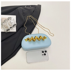 Detail of light blue evening clutch with gold wavy accent and smartphone for scale