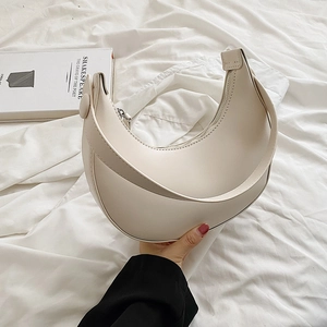 Chic off-white crescent shoulder bag in soft leather texture on white fabric