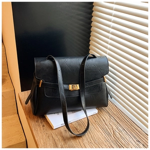Close-up of black leather tote bag with a golden square metal lock on a wooden ledge
