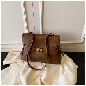 Detail view of brown vintage shoulder bag showing golden square lock on leather texture