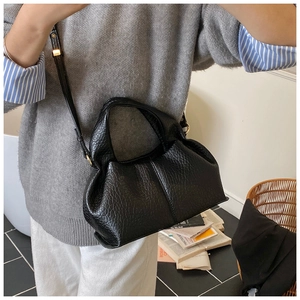 Detail of black pleated faux leather bag with adjustable strap and textured finish