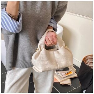 Detail of cream white textured leather handbag with gold metal hardware and top handle