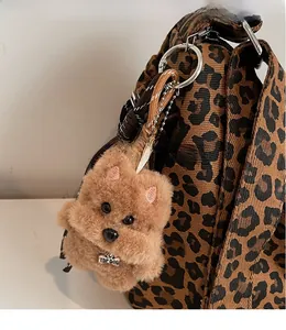 Detail of plush puppy keychain with Top Dog metal tag hanging on a leopard print bag