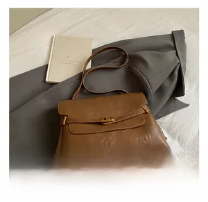 Detail of vintage brown leather tote bag with elegant gold metal twist lock and texture