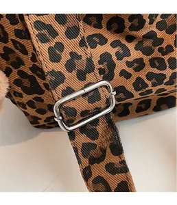Detailed close-up of a leopard print bag with silver square metal buckle and woven strap