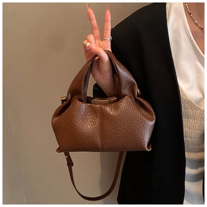 Detail of dark brown pebble leather handbag featuring a soft pleated structure and handle