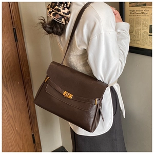 Close-up of vintage dark brown tote bag featuring golden buckle and leather texture