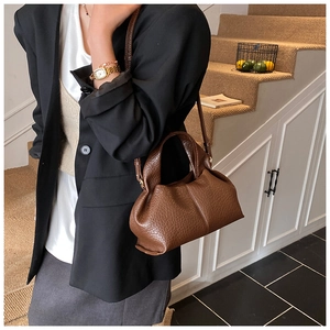 Close-up of brown litchi pattern leather bag with natural pleats and soft texture