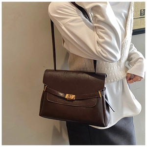 Detail view of large brown tote bag featuring elegant golden buckle on shoulder strap