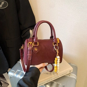 Retro burgunderrote Kissentasche mit Ziernähten und goldener Hardware auf silbernem Koffer