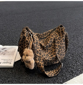Detailed close-up of leopard print canvas shoulder bag with a brown plush bear charm