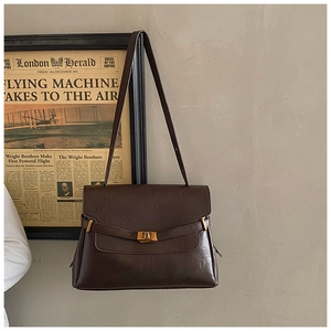 Close-up of a dark brown vintage shoulder bag with a sleek gold rectangular metal lock