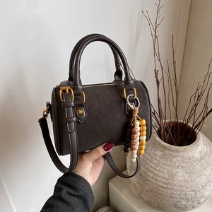 Dunkelbraune Boston-Tasche in Zylinderform mit Lychee-Struktur und Ethno-Anhänger