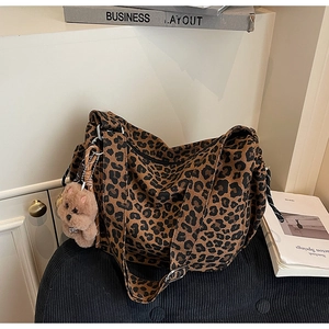 Detail of leopard print canvas bag with adjustable wide strap and plush bear charm