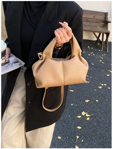Close-up of a camel lychee pattern leather dumpling bag with elegant pleats and shoulder strap