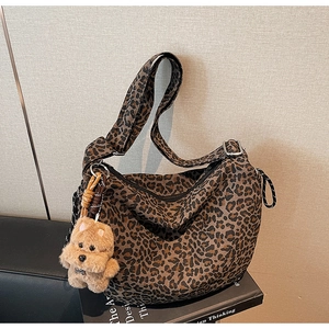 Detail of leopard print hobo bag with wide strap and cute plush dog charm accessory