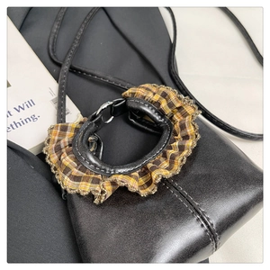 Close-up of British style plaid pet collar with lace trim on a stylish leather handbag