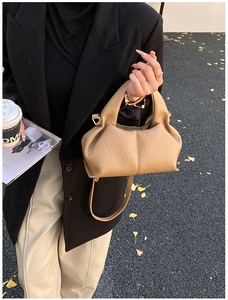 Detailed macro view of khaki leather dumpling bag with elegant pleats and gold hardware