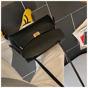 Detail shot of black leather tote bag with elegant gold metal buckle in street style setting