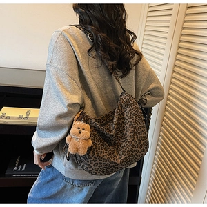 Leopard print crossbody bag styled with a brown teddy bear charm on casual grey sweater