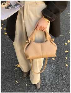 Close-up of camel brown lychee leather texture and gold hardware on pleated tote bag