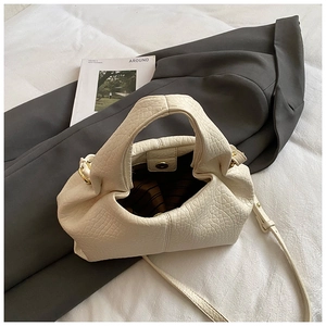 Detail view of cream pleated dumpling bag with magnetic clasp and striped lining