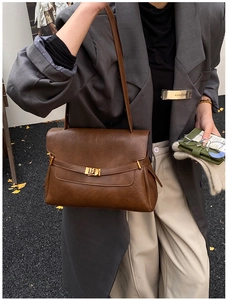 Detail of retro brown leather tote bag featuring a high-quality gold twist lock closure