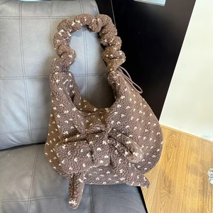 Detail of plush winter tote bag with large bow and white heart patterns on brown faux fur
