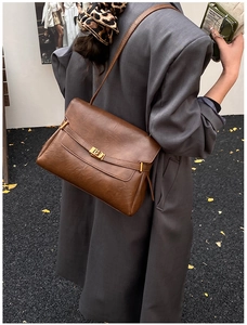 Detail of a brown leather tote bag featuring a vintage gold rectangular metal clasp lock