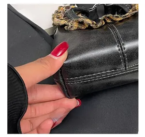Macro shot of precise stitching on black leather handbag with checkered lace trim