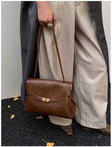 Close-up of vintage brown tote bag featuring a decorative strap and gold metal buckle lock