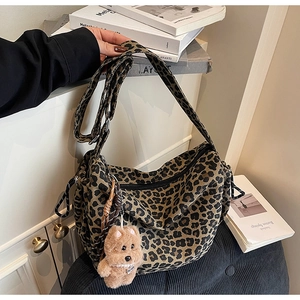 Detail of leopard print crossbody bag with plush bear charm and adjustable strap