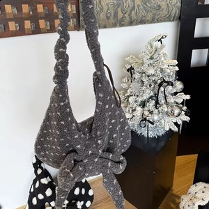 Detail of grey plush shoulder bag with white polka dots and oversized bow decoration