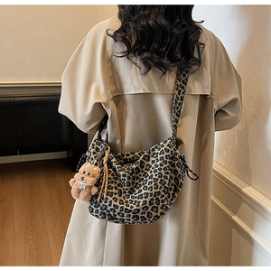 Detailed view of leopard print crossbody bag featuring a plush bear charm on the strap