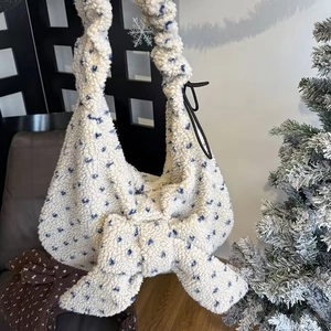 Detail of plush faux shearling tote bag with a large bow and soft wool texture