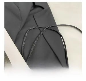 Detail of a black synthetic leather bag strap with a fine textured finish and stitching